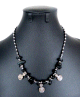Collier artisanal marocain avec pierres noir, agrémenté de petites breloques tourbillon en métal argenté Collier artisanal marocain avec pierres noir, agremente de petites breloques tourbillon en metal argente