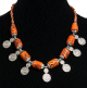 Collier ethnique artisanal cylindres imitation corail orange avec armatures en métal argenté ciselé agrémenté de pendentifs tourbillon spirale argentés Collier ethnique artisanal cylindres imitation corail orange avec armatures en metal argente cisele agremente de pendentifs tourbillon spirale argentes